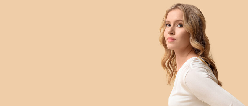 Blonde young woman with curly hair on beige background