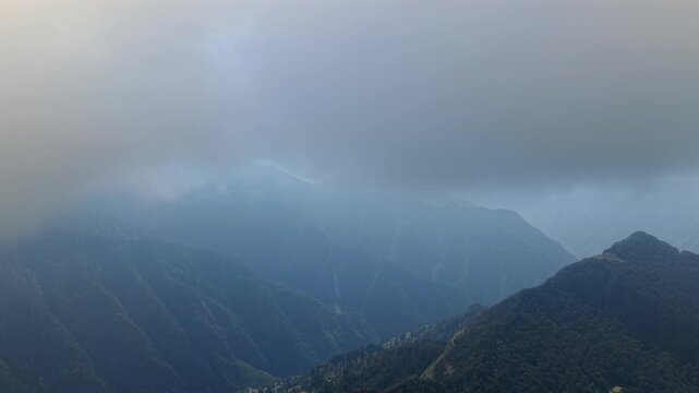 Aerial view of mist covered Himalayan mountain valleys and forested ridges near Parvati Valley, Himachal Pradesh, India.