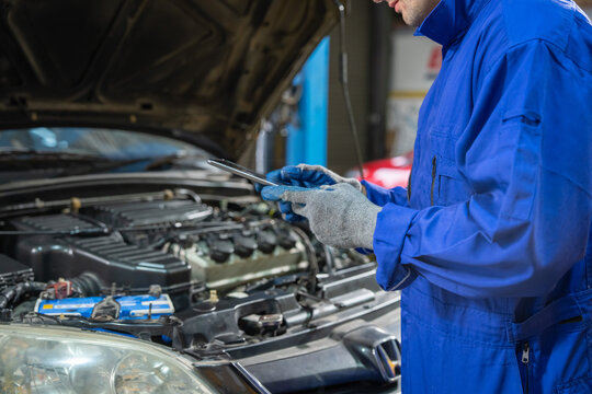 Automotive mechanic repairing vehicle in workshop technical inspection indoor professional environment