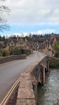 bridge over the river the historic village of Castle Combe in the Cotswolds, England, featuring traditional stone cottages and a scenic stone bridge over a river.