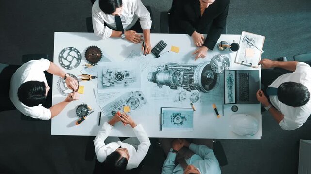 Top view of engineer pointing at turbine engine at meeting table with equipment. Aerial view of professional project manager talking and discussing about electronic generator system. Alimentation.