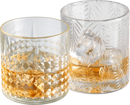 Two textured glass tumblers with amber liquid and ice isolated on transparent background