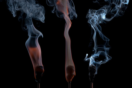 Active torches with hot smoldering embers emitting dynamic wisps of smoke against a dark backdrop. Concept of burning energy, heat, and power.