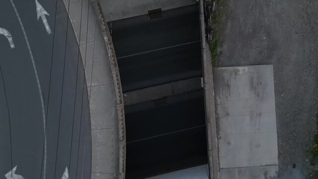 cars drive under overpass through tunnel aerial view looking down urban car infrastructure next to train tracks port jervis new york underpass ny pike street