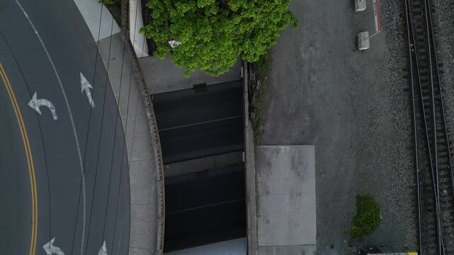 cars drive under overpass through tunnel aerial view looking down urban car infrastructure next to train tracks port jervis new york underpass ny pike street
