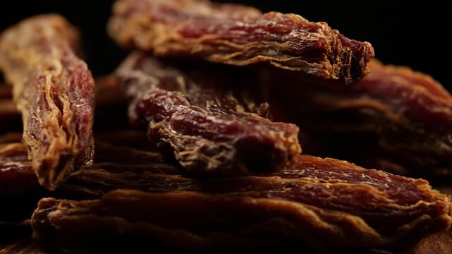 Macro Close-Up of Savory Dried Beef Jerky Strips Stacked on a Dark Background. High-Protein Snack Food Detail.