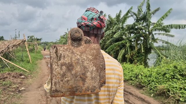 Back View of Farmer Standing with Hoe and Gamcha on Head