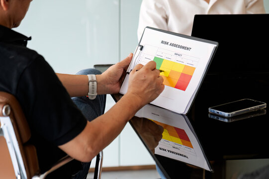 Business colleagues discussing corporate risk management matrix during meeting.