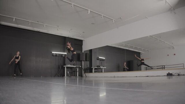 Acrobatic young female ballet dancers training in a modern dance studio