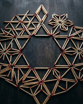 Geometric mandala pattern created with wooden matches on dark wood surface