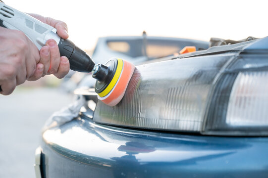 The process of polishing car headlights outdoors. 