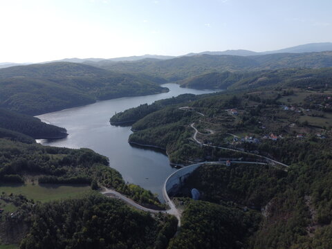 Aerial view of dam and reservoir surrounded by green forest hills in Serbia near Uzice. g.