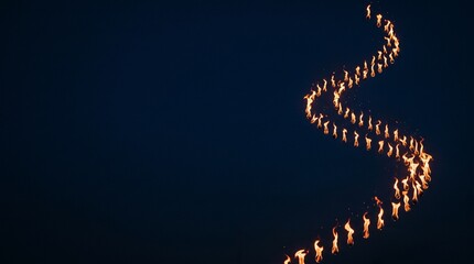Obraz premium Group of People Carrying Torches in a Winding Line at Night Creating a Luminous Path