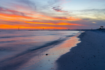 Obraz premium Seascape. Colorful beach sunset with vibrant orange and pink clouds reflected on calm ocean water. Peaceful sandy shoreline at dusk, tropical coastal landscape. Scenic nature. Travel destination