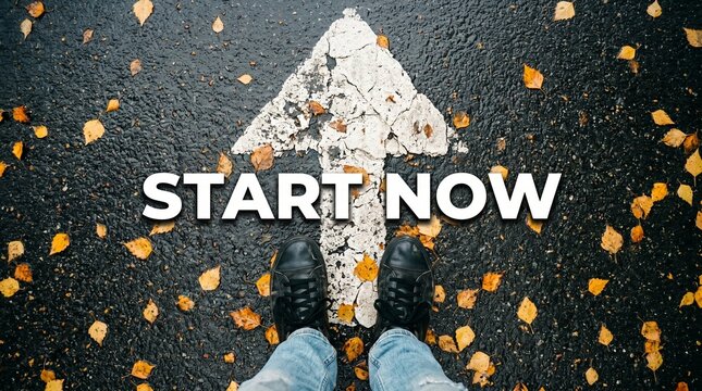 Start Now: A person stands on an asphalt road marked with a white arrow pointing forward, urging action. Autumn leaves are scattered across the ground.
