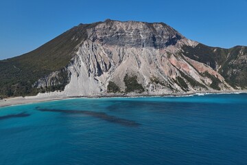 Aerial drone photo of Satoyama volcano and turquoise bay at Kozushima Island, Tokyo, Japan © AeroSkope