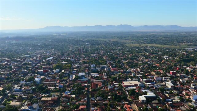 Drone aerial view of Villarrica urban landscape with streets, buildings, trees, and mountain range on horizon.