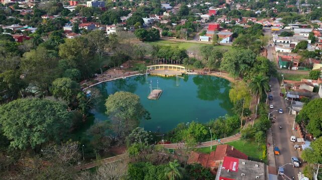 Panoramic orbit aerial overlooking Ykua Pyta lake in Manuel Ortiz Guerrero park, Villarrica, Paraguay