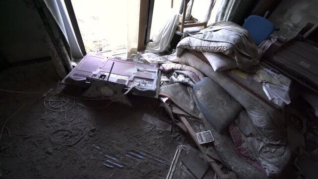 Dusty abandoned room in Fukushima with scattered belongings and debris.