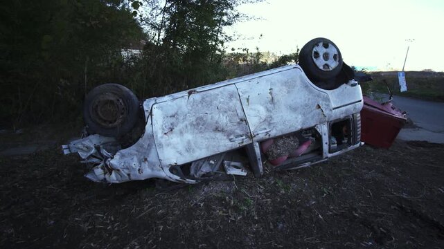 Rusted, overturned white car lies abandoned in a desolate area of Fukushima.