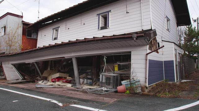 Partially collapsed two-story building and debris after an earthquake in Japan.