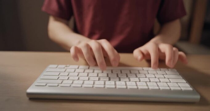 Person typing on wireless keyboard at desk for digital office work captured in slow motion.