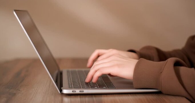 Woman hands typing on laptop keyboard close-up slow motion, student working on computer.