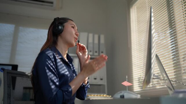 Professional female customer service representative talking on a headset during a video call. Friendly sales operator working from the office