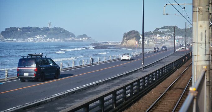 Coastal Road and Railway Track Side by Side Near Ocean Waves In Japan - Wide Shot