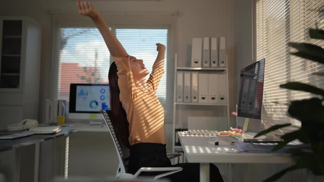 Businesswoman feeling tired and stretching her body while sitting in an ergonomic chair. Employee taking a short break from computer work