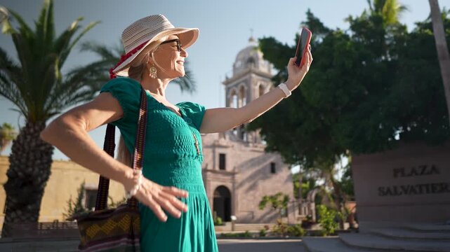 Senior woman enjoys taking pictures at the mission church in Loreto Baja California Sur Mexico during her sightseeing adventure.
