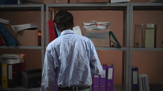 Dim archive room with shelves of binders and boxes