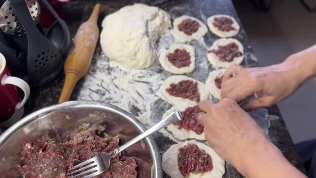 Women's hands forming traditional Tatar pastries called belyashi. Top view..