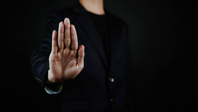 Business professional showing a stop hand gesture, symbolizing prohibition, rejection, security, compliance, risk prevention, fraud protection, privacy control, warning, boundary setting.