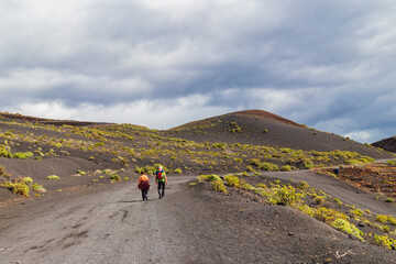 Fototapeta premium Rear view of a tourist couple walking along the famous Ruta de los Volcanes hiking trail on La Palma island, Canary Islands, Spain