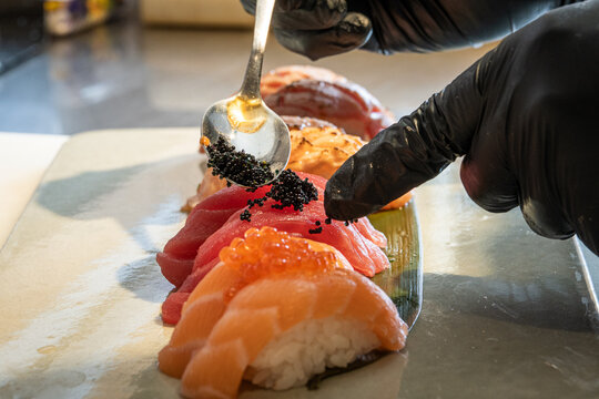 Sushi Artistry in the Kitchen. Close-up of Sushi Preparation with Black Gloves