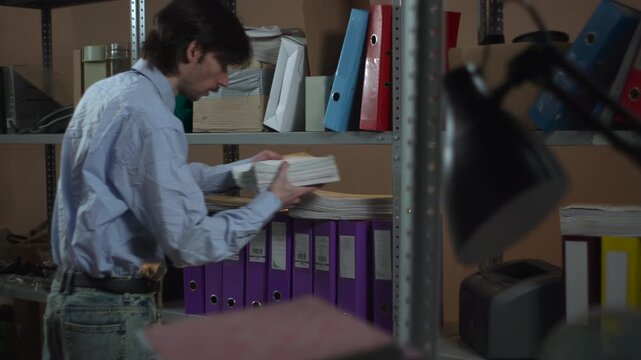 Office storage shelves with colorful binders behind a blurred desk lamp