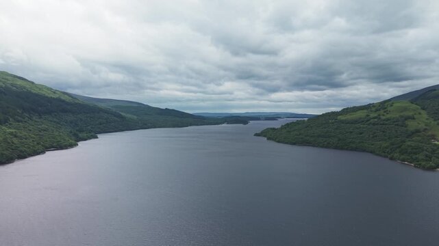Dramatic aerial view of Firkin Point at Loch Lomond, Scottish Highlands. Scenic aerial shot of the wide lake water, forested mountain shores, and overcast cloudy sky.
