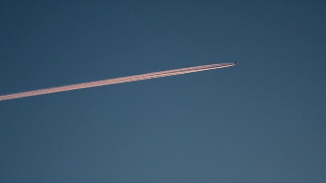 Diagonal airplane contrail cutting through clear blue Arctic sky above Norway