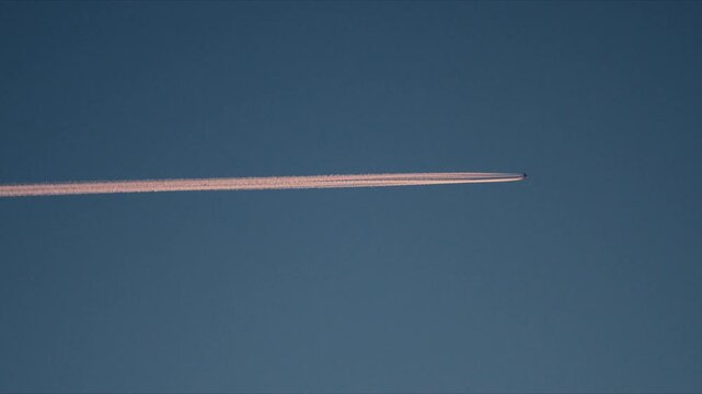 Airplane contrail stretching across clear blue Arctic sky above Norway landscape
