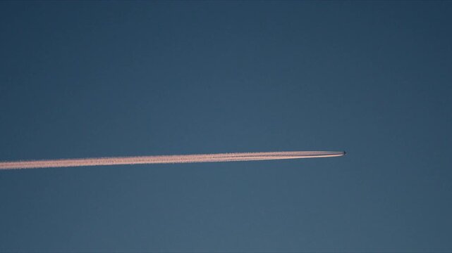 Long airplane contrail crossing soft blue Arctic sky over Norway wilderness