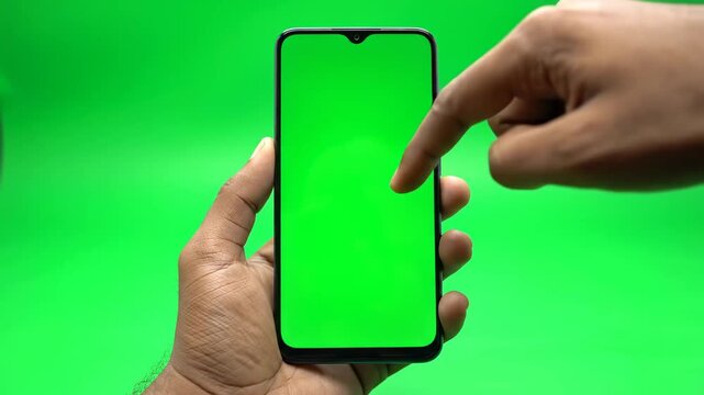 Professional Chroma Key Setup: Hand Holding a Modern Smartphone with Green Screen Display Against a Solid Green Background, Ideal for Video Editing and App Demonstrations.