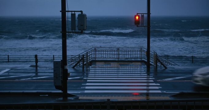View of wet crosswalk and majestic ocean waves during storm in Japan
