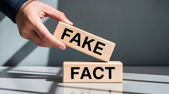 Hand placing wooden block with fake on top of fact block on table