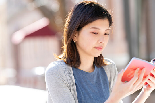 街の中で座って本を読んでいる女性