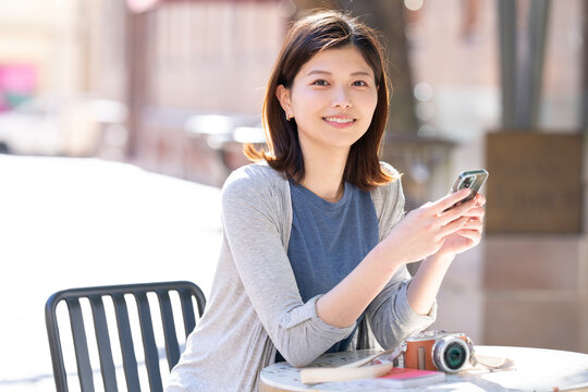 街の中で座ってスマホを見ている女性