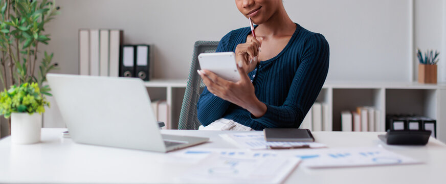 Black woman finding solutions at desk, calculating finances, managing budget, planning investments, and analyzing business growth while working in a modern office