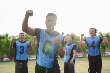 Obraz premium Excited soccer player raising fist and shouting to celebrate victory. Teamwork, success, and active lifestyle concept during a sports match on an outdoor field.