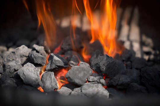 Close-up of glowing hot coals and vibrant flames in a fireplace.