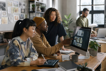 Fototapeta premium Four colleagues collaborate around a large monitor